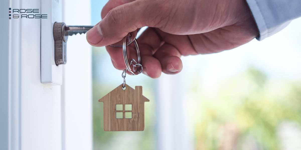 person putting key in lock with house shaped charm